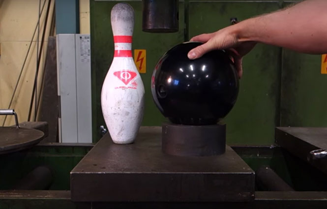 Κορίνα και μπάλα του Bowling στην υδραυλική πρέσα